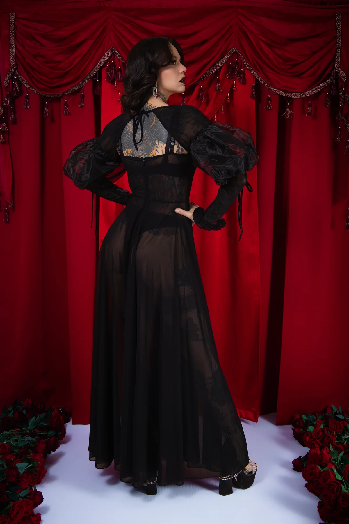 Woman in a black evening gown standing against a red curtain backdrop