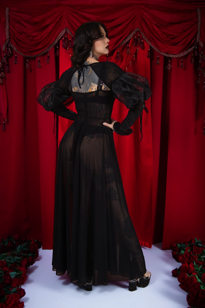 Woman in a black evening gown standing against a red curtain backdrop