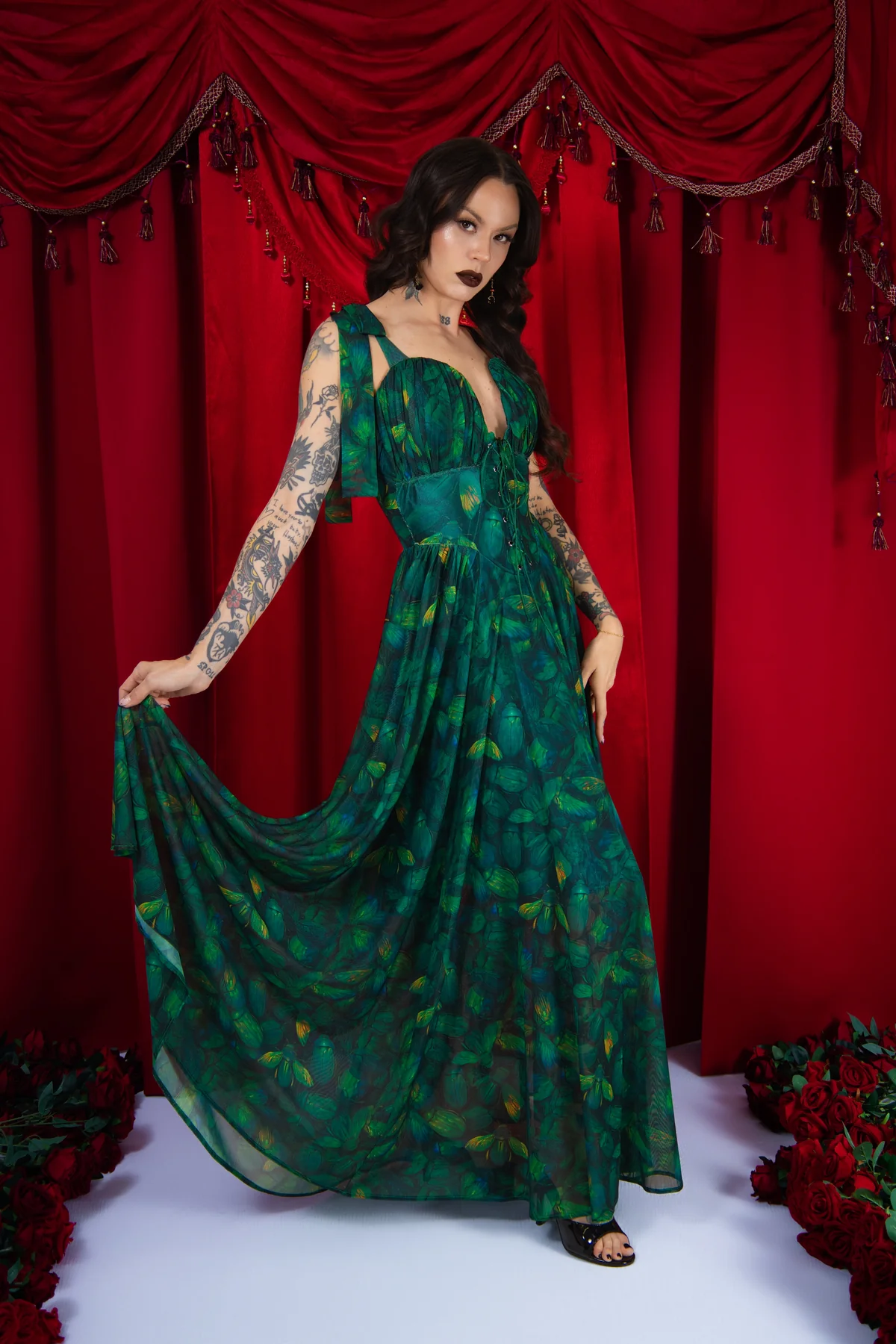 Woman in a green dress posing against a red curtain backdrop