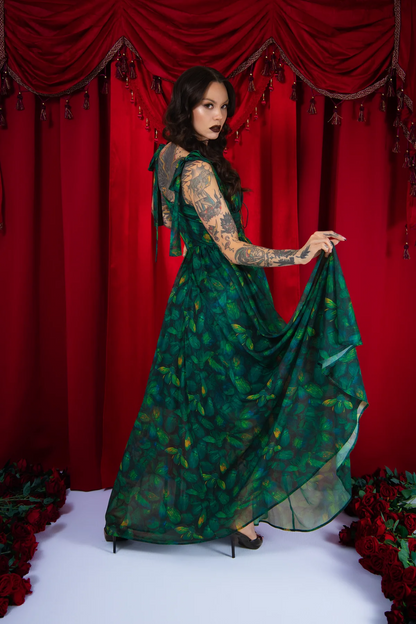 Woman in a green dress with floral pattern against a red curtain backdrop