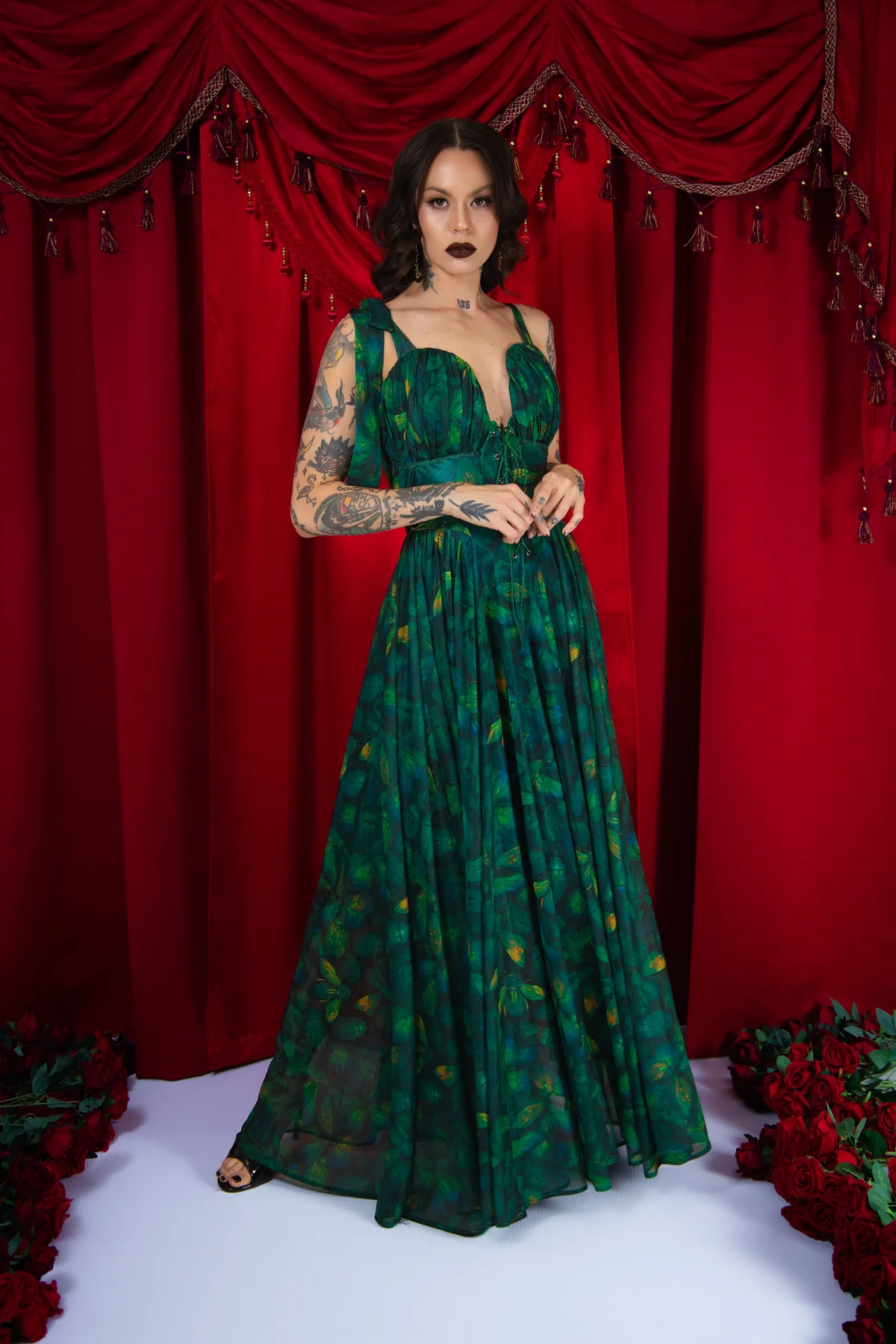 Woman in a green dress standing in front of a red curtain