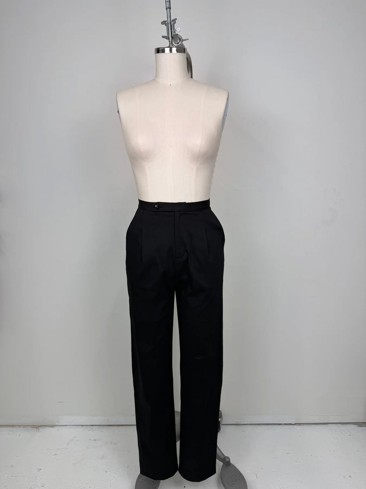 Black wide-leg trousers displayed on a cream dress form mannequin against a plain light gray wall.