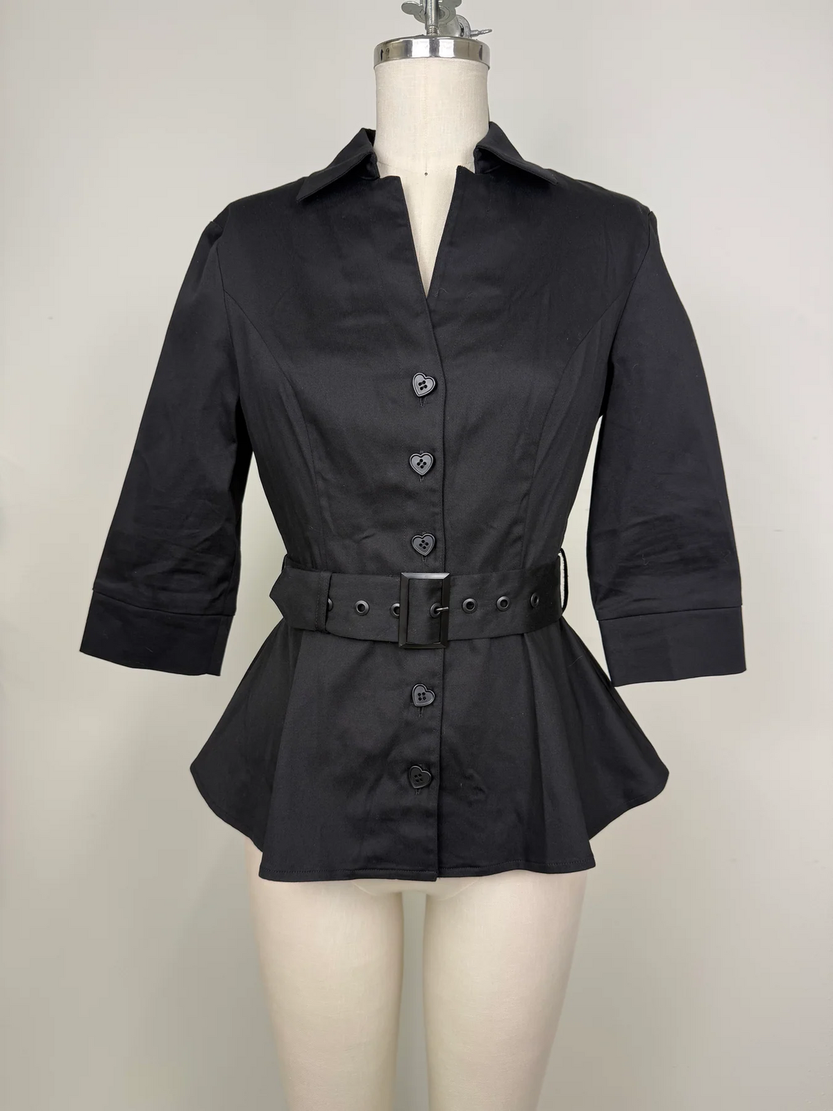 A black women's collared shirt jacket with three-quarter sleeves, a matching fabric belt with a silver buckle, and front button closure, displayed on a cream mannequin against a light gray background.