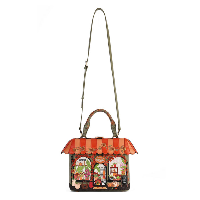 A Gucci handbag with a colorful storefront illustration on the front, featuring an orange and red striped awning, top handles, and a long shoulder strap, shown against a plain white background.