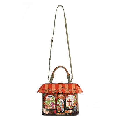 A Gucci handbag with a colorful storefront illustration on the front, featuring an orange and red striped awning, top handles, and a long shoulder strap, shown against a plain white background.