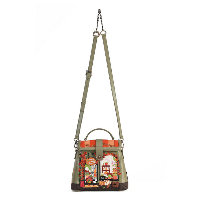 An olive green leather shoulder bag with a top handle, adjustable shoulder strap, and a colorful embroidered patchwork design on the front depicting a street scene with a red double-decker bus, a red telephone booth, and a white rabbit.