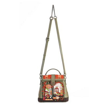 An olive green leather shoulder bag with a top handle, adjustable shoulder strap, and a colorful embroidered patchwork design on the front depicting a street scene with a red double-decker bus, a red telephone booth, and a white rabbit.