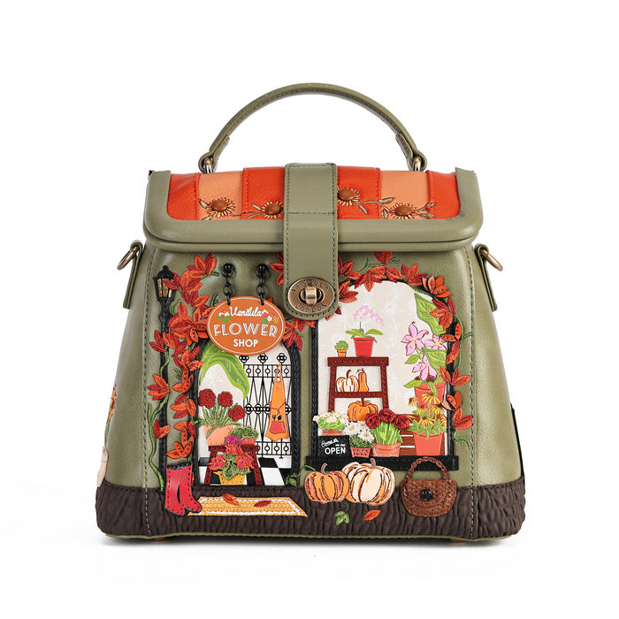 An olive green handbag with a top handle, featuring a detailed embroidered design of a flower shop storefront with pumpkins, flowers, and autumn leaves.
