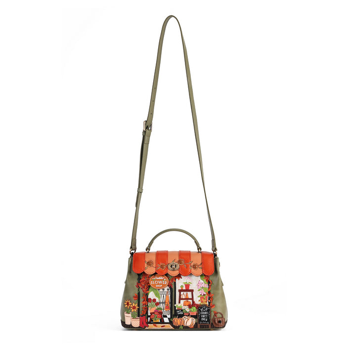 An olive green leather shoulder bag with a top handle and a long adjustable strap, featuring a highly detailed, colorful storefront illustration on the front flap.