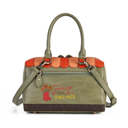 An olive green handbag with a scalloped orange leather top trim, a brown textured base, and a matching shoulder strap. The front features a colorful embroidered design with red boots, yellow text, and a sunflower, reading 'in a world full of weeds, be a SUNFLOWER'.