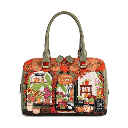 A structured handbag with olive green handles and trim, featuring a highly detailed, colorful autumn-themed illustration on the front depicting a flower shop, pumpkins, and fall foliage.