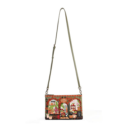 A crossbody handbag with a wide, colorful vintage-style illustration on the front panel and a slim olive green strap, shown against a plain white background.