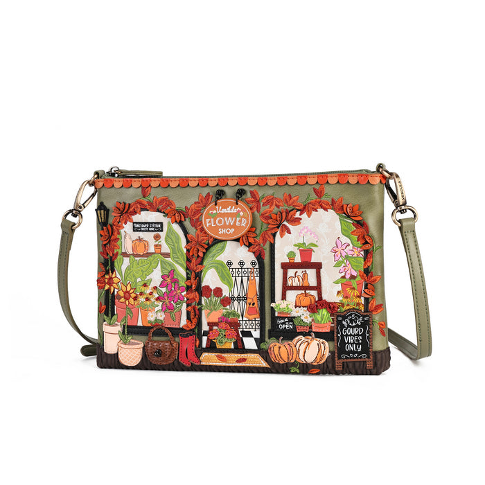 A rectangular shoulder bag with a detailed, colorful illustration of a flower shop facade. The bag features an olive green base, scalloped orange trim, and a printed design with autumn leaves, potted plants, pumpkins, and flowers.