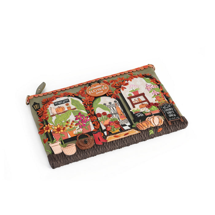 A rectangular zip pouch with a detailed autumn-themed patchwork design featuring pumpkins, flowers, a chalkboard sign, and a rustic brown braided trim along the bottom edge, shown on a plain white background.
