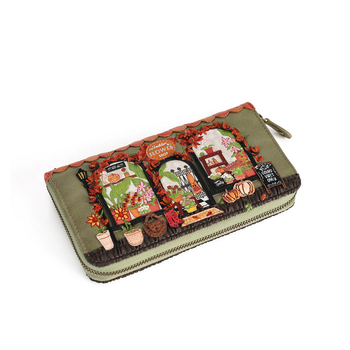 An olive green zip-around wallet featuring a detailed autumn-themed illustration with pumpkins, potted plants, and a rustic archway, shown on a plain white background.