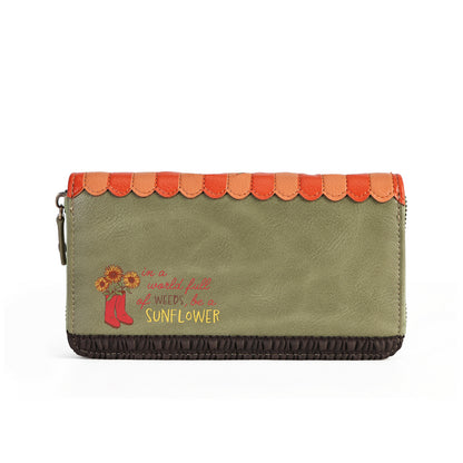An olive green faux-leather zip-around wallet with a scalloped orange top trim, a dark brown ruffled bottom edge, and a western-style sunflower and boots graphic on the front.
