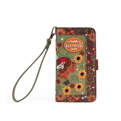 A floral wallet phone case with a wrist strap, featuring a green center panel with a hedgehog, yellow flowers, and a brown patterned border, complete with an oval 'Hedgehog's Flower Shop' logo patch.
