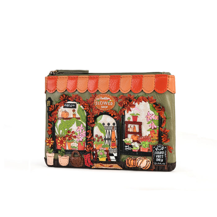 A small zip-around pouch featuring a detailed embroidered illustration of a flower shop facade, with orange scalloped trim, floral arches, pumpkins, and a chalkboard sign, shown on a plain white background.