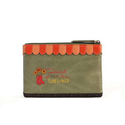An olive green zippered pouch featuring a scalloped orange and red trim along the top, a dark brown ruffled bottom edge, and a graphic on the front with red boots, sunflowers, and the text 'in a world full of weeds, I am SUNFLOWER'.
