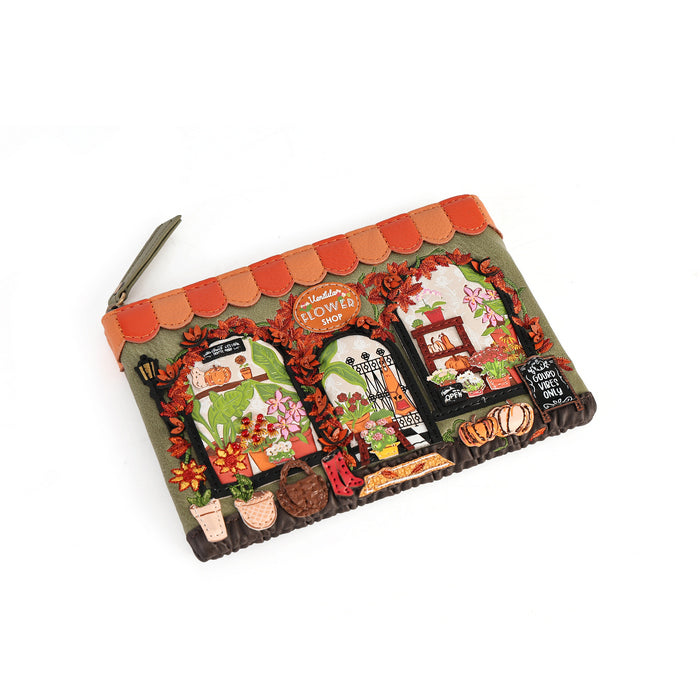 A small zippered pouch featuring a colorful embroidered design of a flower shop facade with flowers, plants, and decorative elements, shown on a plain white background.