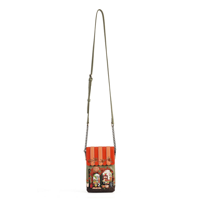 A small crossbody bag with a long olive green strap and a colorful printed front panel depicting a street scene under orange awnings, shown on a plain white background.