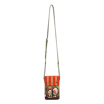A small crossbody bag with a long olive green strap and a colorful printed front panel depicting a street scene under orange awnings, shown on a plain white background.