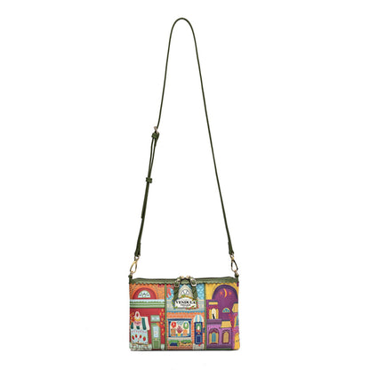 A small crossbody bag with a colorful, whimsical storefront pattern in red, yellow, green, and purple, featuring an olive green shoulder strap and gold-tone hardware, shown against a plain white background.