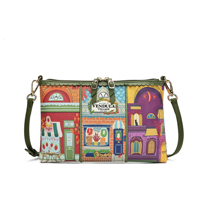 A rectangular shoulder bag with an all-over colorful architectural storefront print, olive green trim and strap, and a central metal plaque reading Vendula Village.