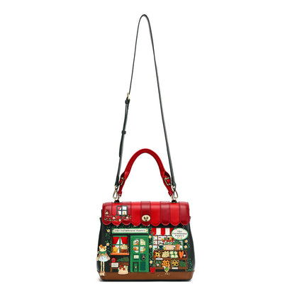 A structured handbag with a red top handle and a long black shoulder strap, featuring a colorful illustrated storefront design on the front and a red scalloped trim along the top.