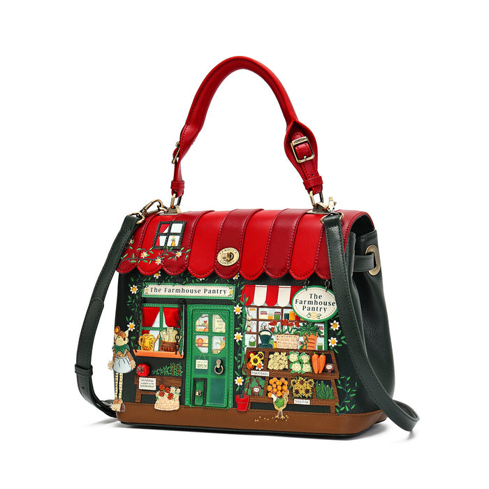 A structured handbag with a red top handle and red scalloped trim, featuring a detailed illustration of a colorful farm market storefront on the front. The bag has dark green shoulder straps, gold-tone hardware, and a brown base, photographed on a clean white background.