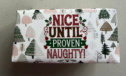 A rectangular box of Christmas-themed soap or lotion with a white background and festive pattern. The front features the text 'NICE UNTIL PROVEN NAUGHTY!' in red and green lettering, surrounded by illustrated pine trees and holly leaves.