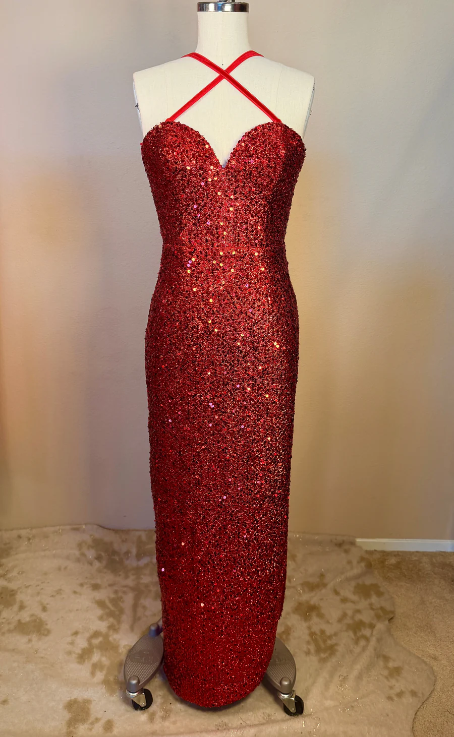 Red sequin evening gown on a mannequin against a plain background