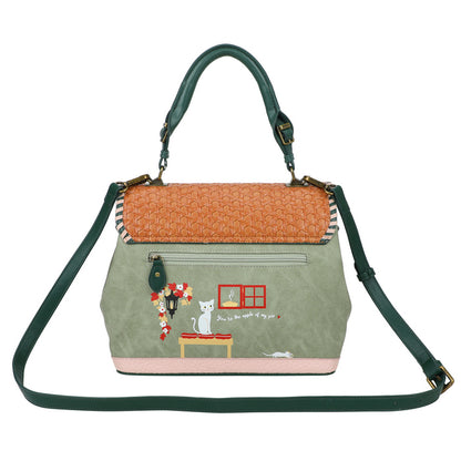 Handbag with green strap and embroidered design on a white background