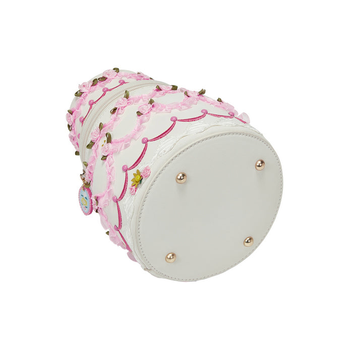 Decorative cylindrical pillow with pink lace and gold beads on a white background