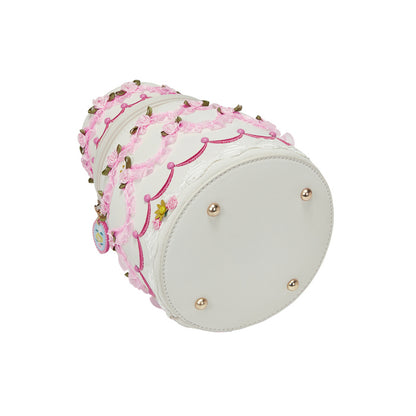 Decorative cylindrical pillow with pink lace and gold beads on a white background