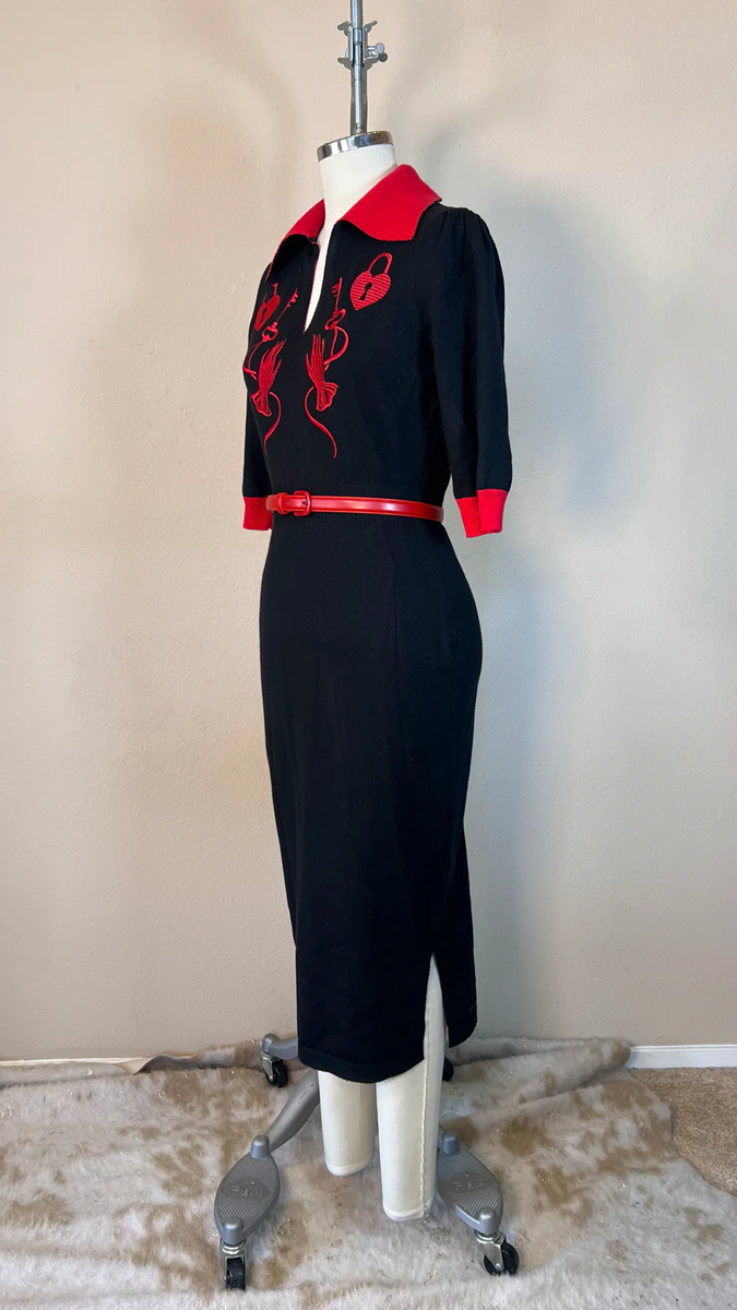 Black dress with red accents on a mannequin against a beige wall.