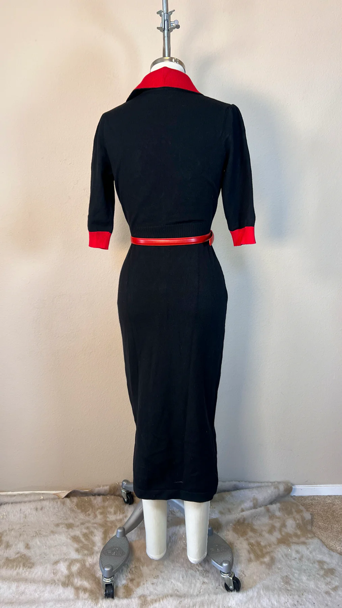Black dress with red accents on a mannequin against a beige wall.