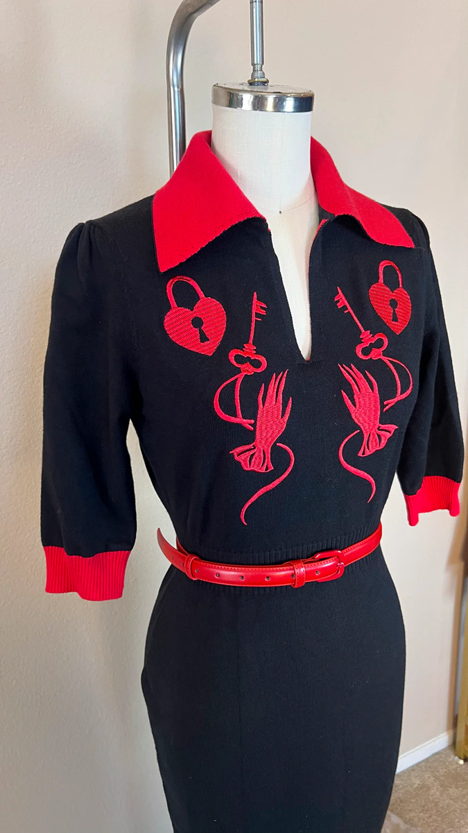 Black dress with red accents on a mannequin against a neutral background