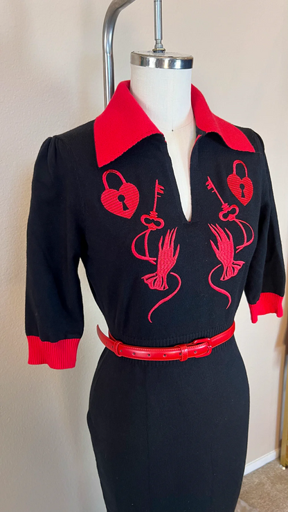 Black dress with red accents on a mannequin against a neutral background