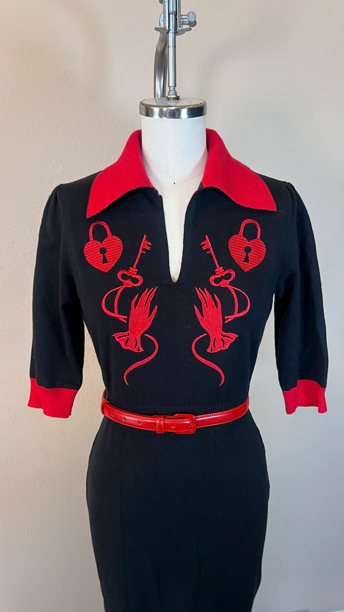 Black dress with red accents on a mannequin against a beige background