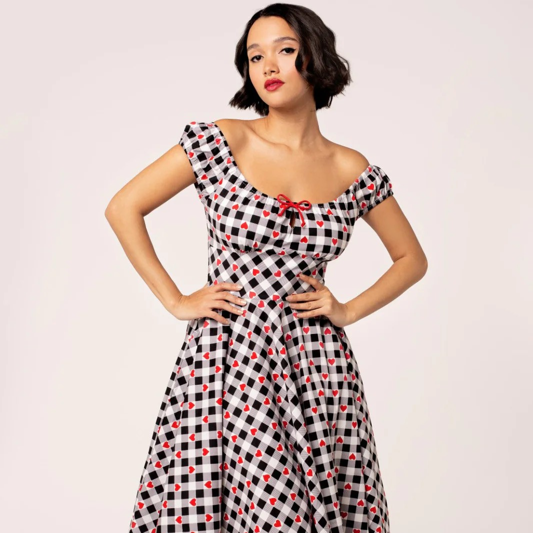 Woman wearing a black and white checkered dress with red accents on a light pink background