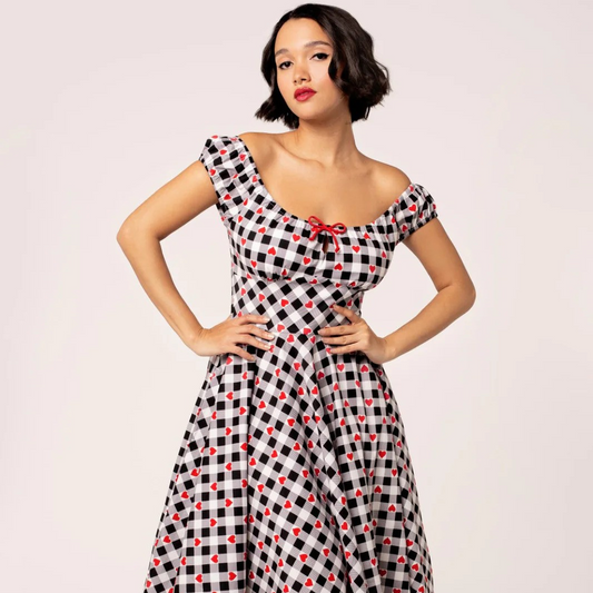 Woman wearing a black and white checkered dress with red accents on a light pink background