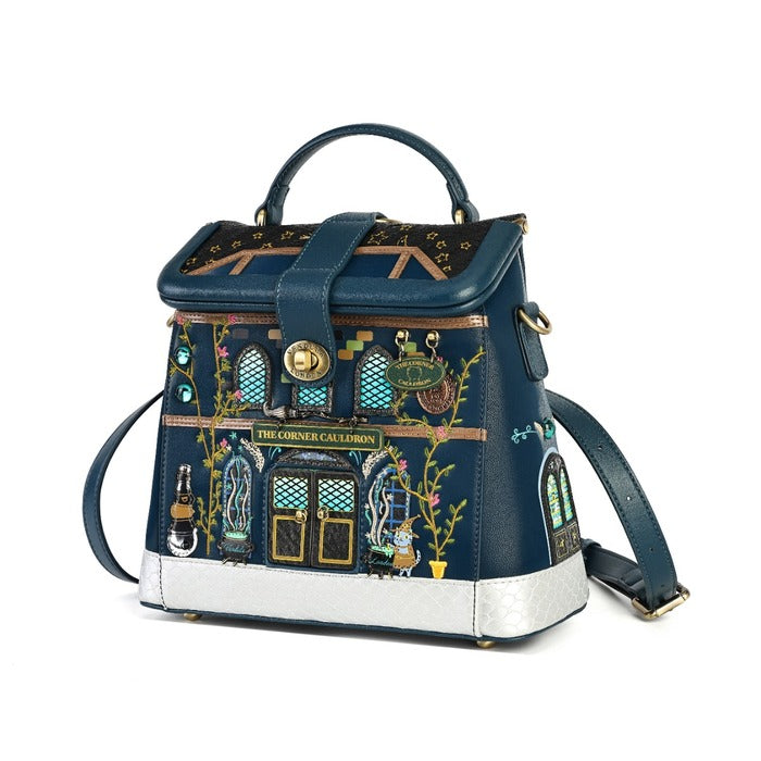 A dark blue handbag designed to look like 'The Crockery Corner' pub from The Great Gatsby, featuring gold and green decorative details, a silver base, and a top handle, shown on a white background.