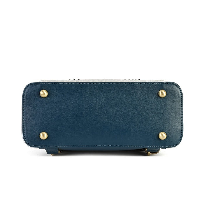 The bottom view of a navy blue leather clutch or handbag, featuring four gold-tone metal studs on the bottom corners and a silver metal trim along the top edge, set against a plain white background.