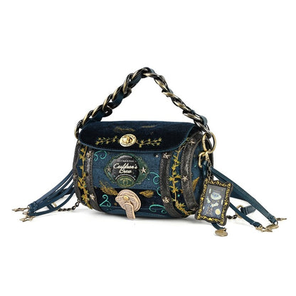 A whimsical dark blue velvet shoulder bag with gold and silver chain straps, featuring embroidered celestial patterns, a gold clasp, and dangling charm details on a white background.