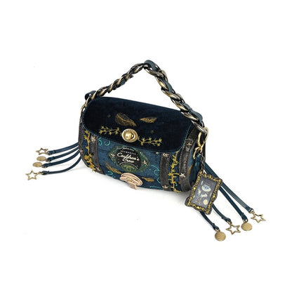A dark blue velvet and patterned fabric shoulder bag with gold-toned hardware, a chain strap, and dangling star charms on a white background.