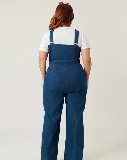 Person wearing blue denim overalls on a plain background