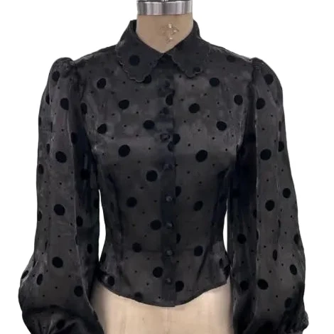 A black sheer long-sleeve blouse with black polka dots, featuring a Peter Pan collar and puffed balloon sleeves, displayed on a beige mannequin torso against a white background.