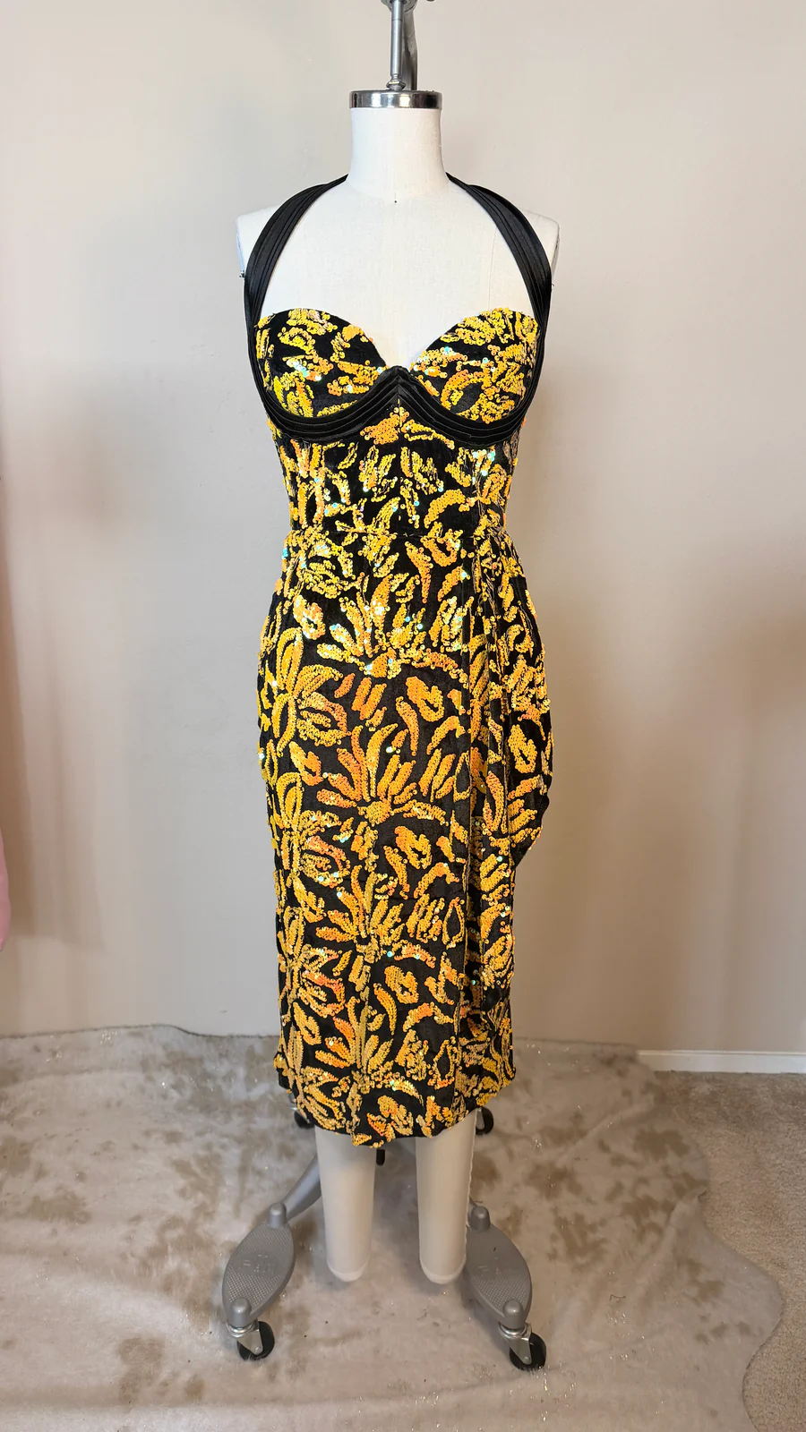 Mannequin wearing a black and yellow patterned dress against a plain background