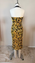 Mannequin wearing a black and yellow patterned dress on a plain background